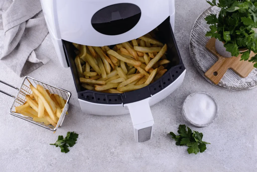A white air fryer with fries and herbs, a healthier alternative to deep frying.